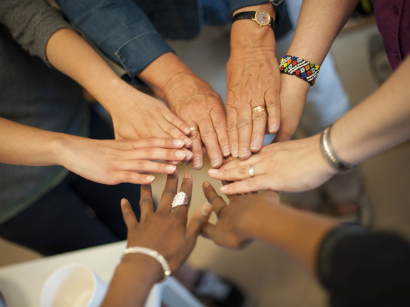 Women put their hands in a circle