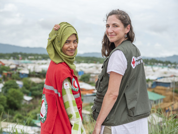 Two upturned women smiling at the camera with a landscape in the background