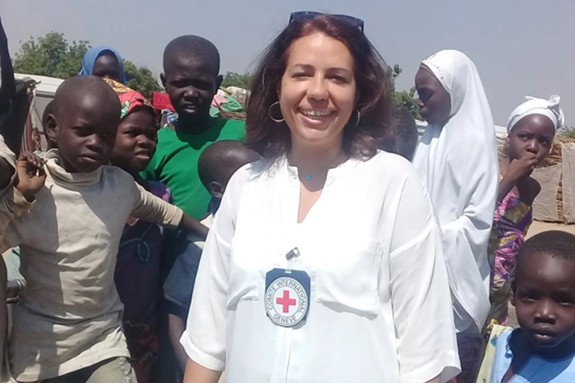 May Mousa smiling at the camera with children in the background