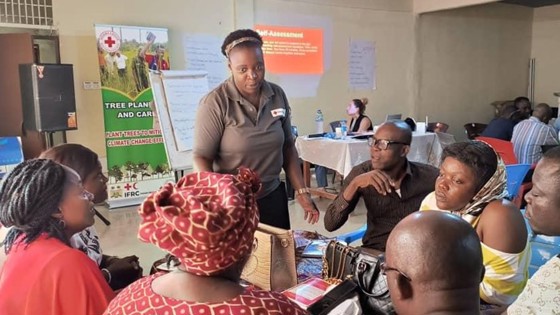 Christina Mangunda speaking to people sitting around a table