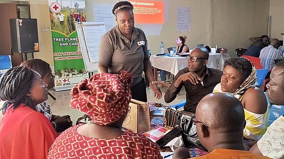 Christina Mangunda speaking to people sitting around a table