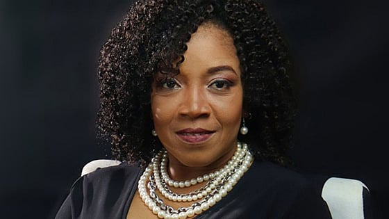 Jill De Bourg smiling at the camera and a black background