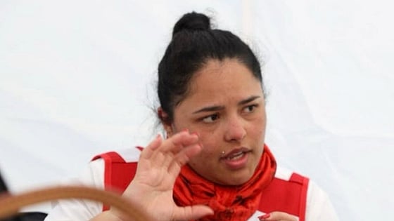 Lina Garcia is talking and moving her hands, while wearing a Red Cross jacket and looking away from the camera.