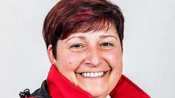 Sylvia is looking into the camera smiling. She is wearing a red jacket.