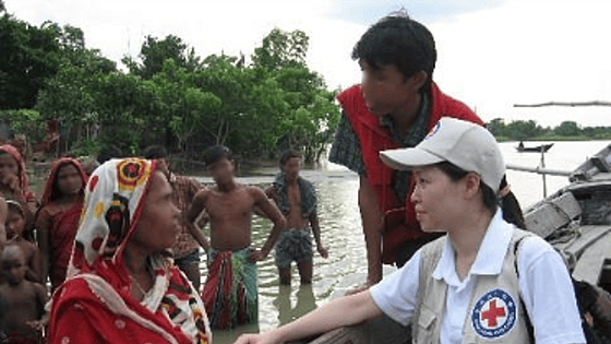 Woman wearing a cap in side profile, men are in the background