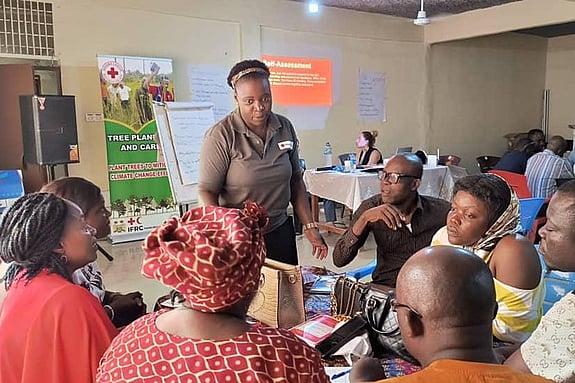 Christina Mangunda speaking to people sitting around a table