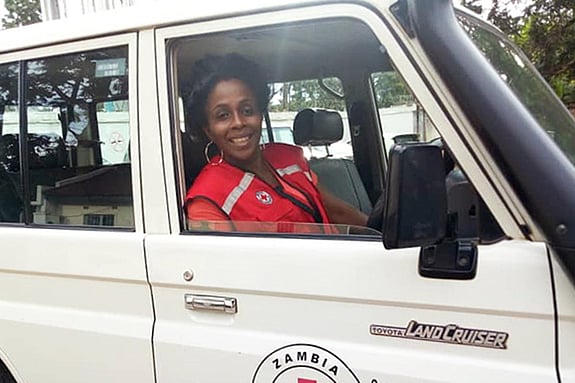 Joan Kamanga with a red jacket in a car