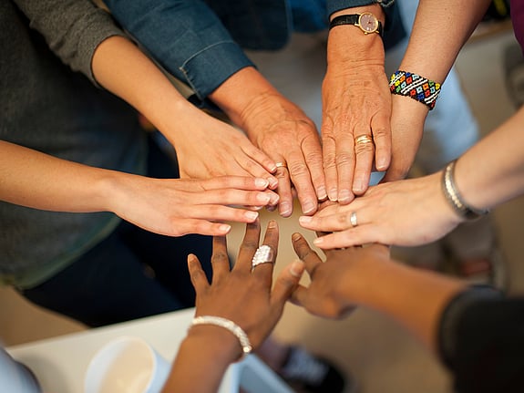 Women put their hands in a circle