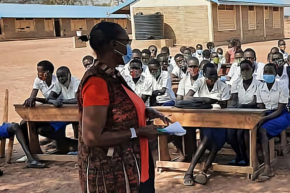 Medoline Lema standing in front of a class of students